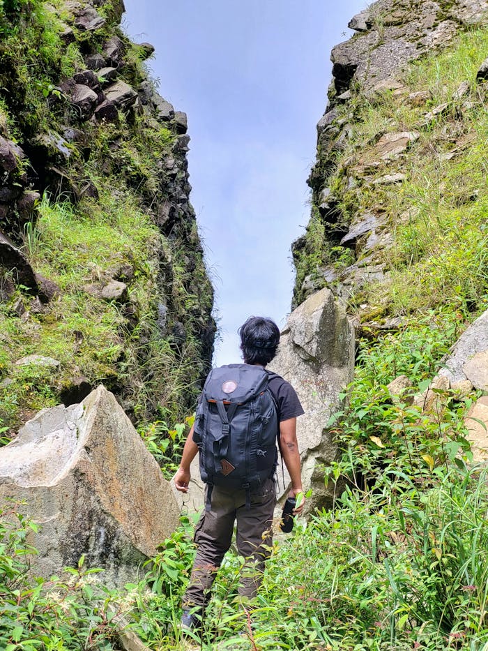 A solo trekker explores the rocky pathways of Dzukou Valley, Nagaland, India, surrounded by lush greenery.