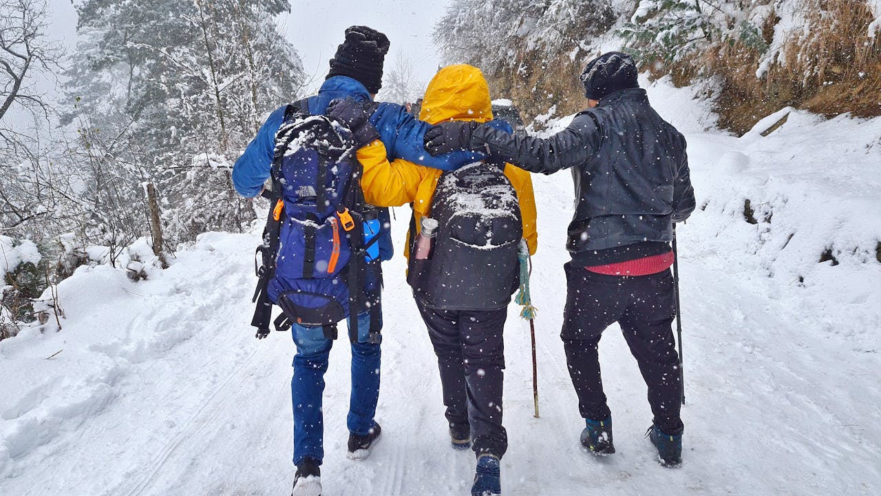 services-02 Group of friends hiking in snowy winter landscape in Sosan, India.